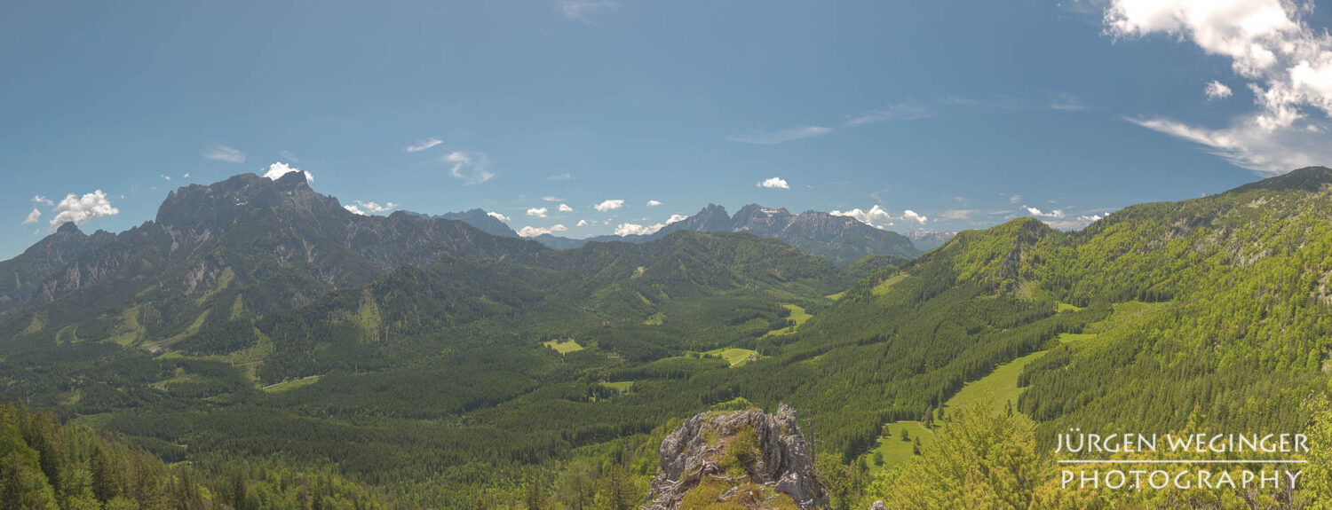 Ausblick auf as Ennstaler Gebirge des Nationalparks Gesäuse vom Lahnkogel aus. Eine Panoramaaufnahme mit blauen Himmel zur Mittagszeit