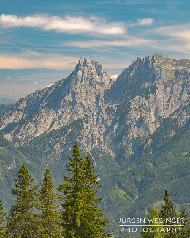 Berg mit blauem Himmel und weissen Wolken mit Wald im Vordergrund. Nationalpark Gesäuse