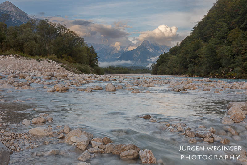 Gebirge mit Wolken mit Fluss im Vordergrund im Abendlicht. Julische Alpen, Rombon Kanin Gruppe, Triglav Nationalpark, Slowenien